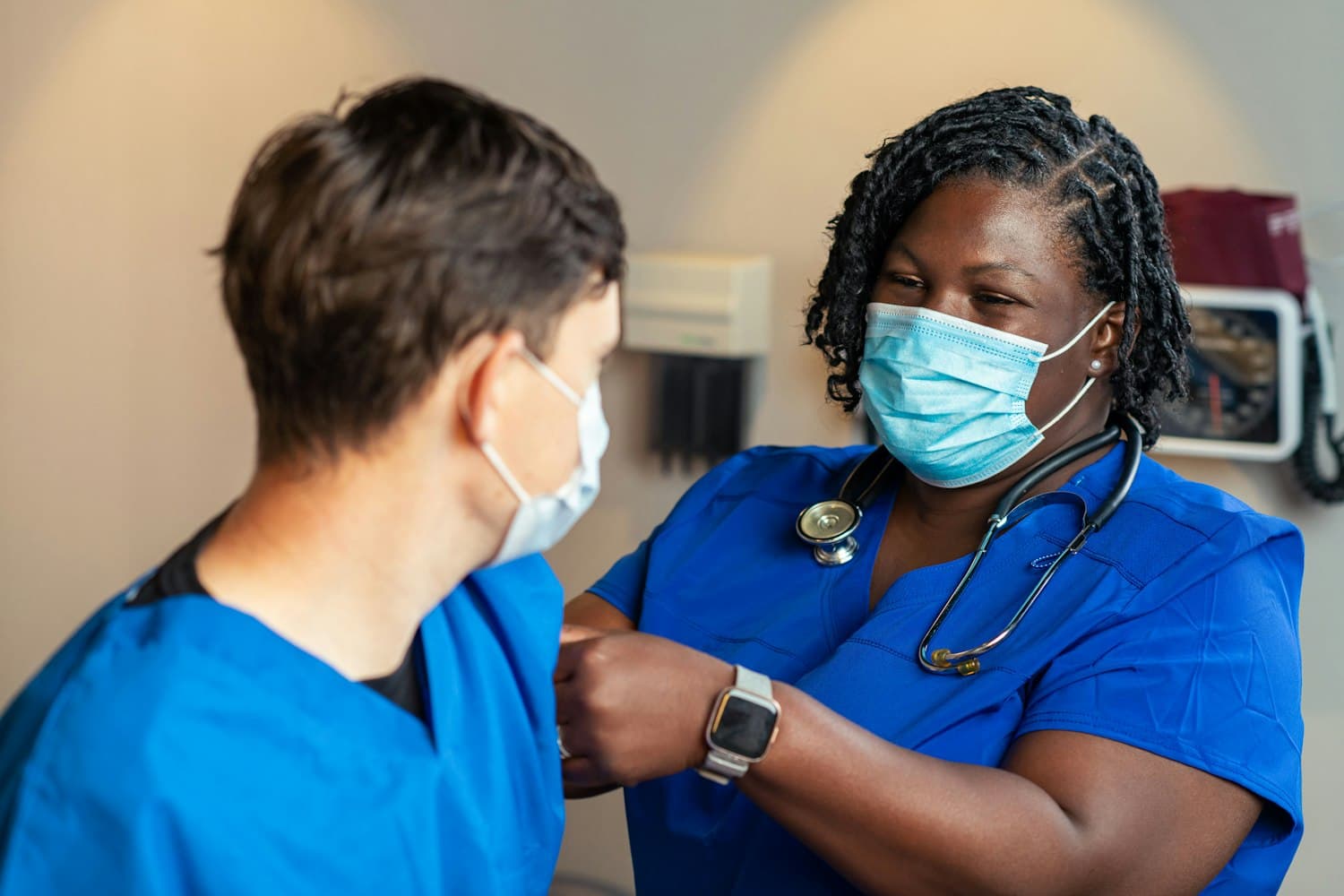 Two clinicians in scrubs collaborating on patient care at a community health center.